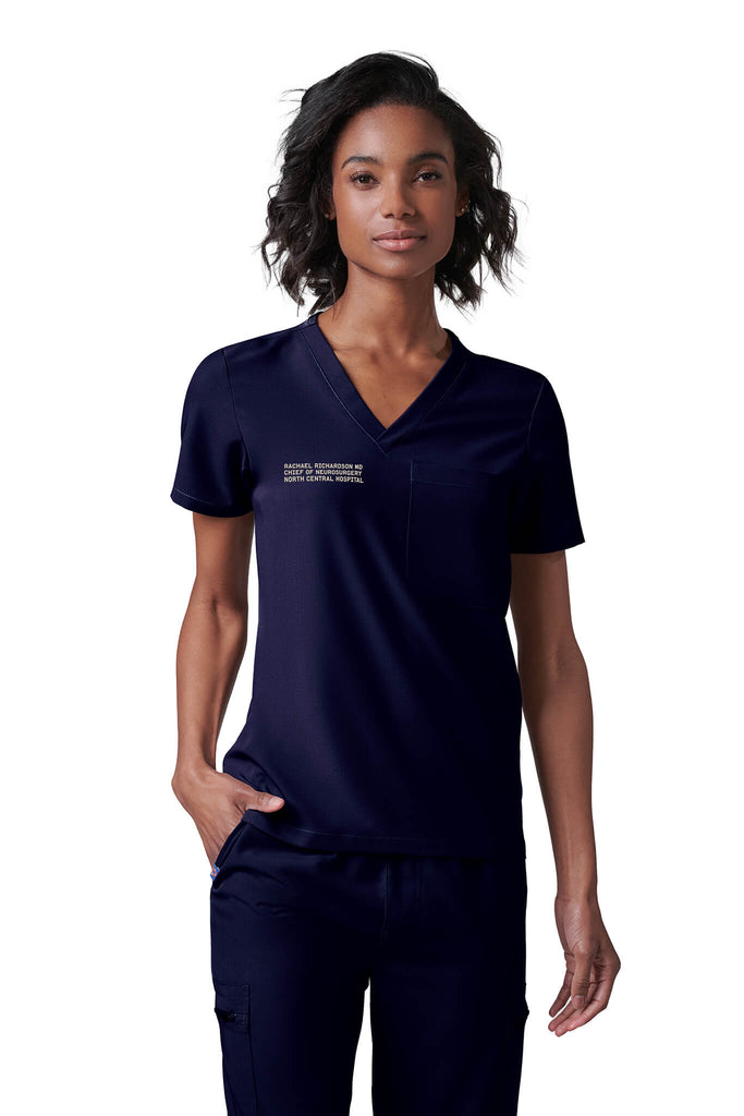 MedTailor Custom Scrubs Collection. A woman is wearing a MedTailor custom scrubs set in Highland Green fabric color.
