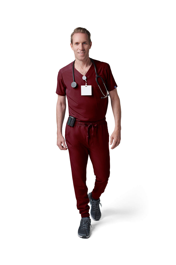 Man wearing MedTailor men's custom scrub pants in Merlot Red color fabric