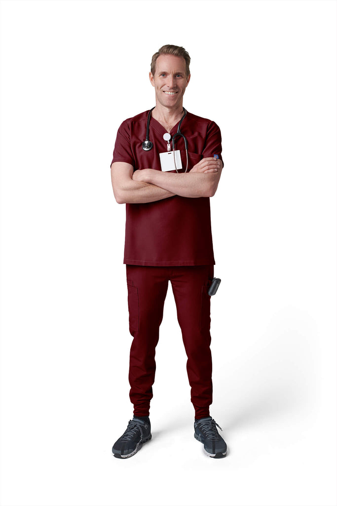 Man wearing MedTailor men's custom scrub pants in Merlot Red color fabric