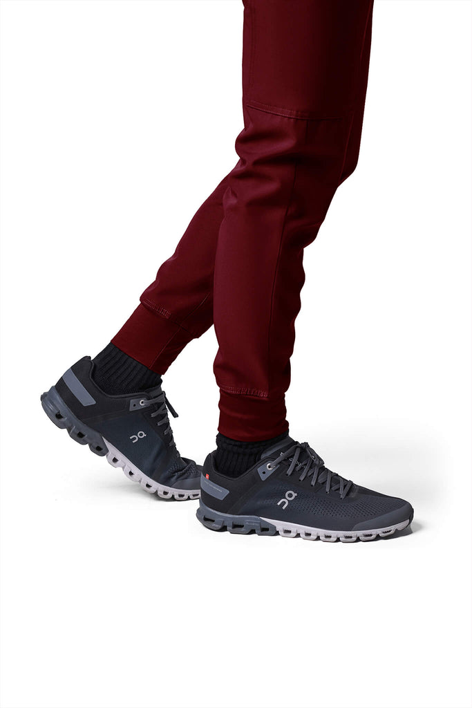 Man wearing MedTailor men's custom scrub pants in Merlot Red color fabric