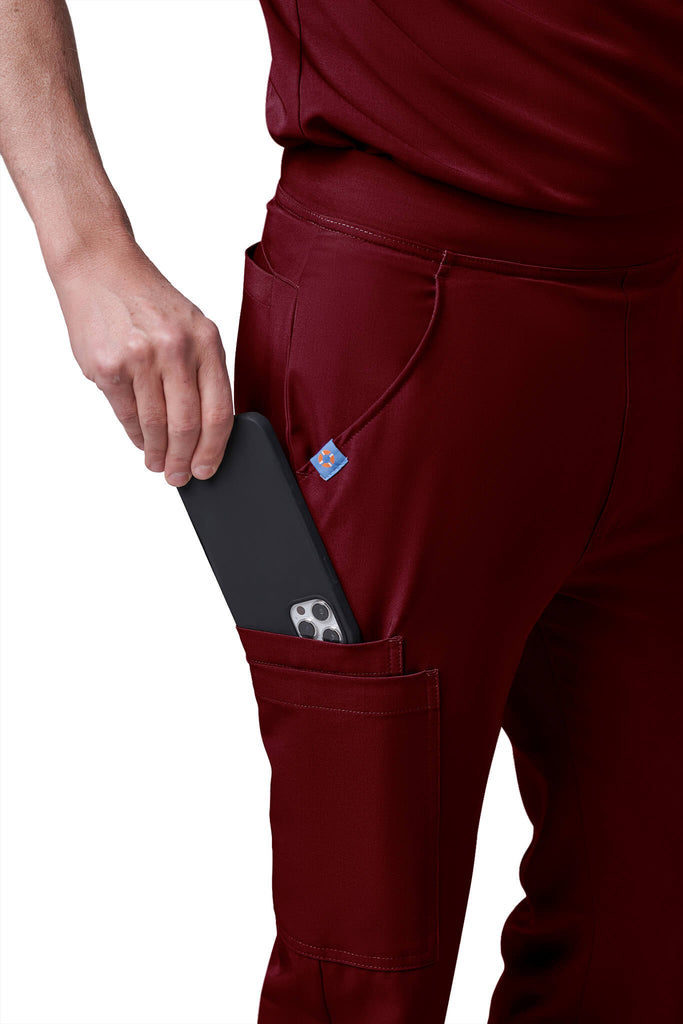 Man wearing MedTailor men's custom scrub pants in Merlot Red color fabric