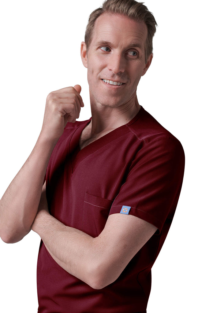 Man wearing MedTailor men's custom scrub top in Merlot Red color fabric