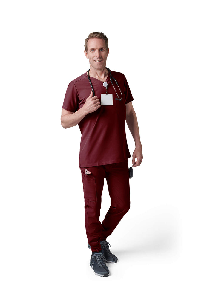 Man wearing MedTailor men's custom scrub top in Merlot Red color fabric