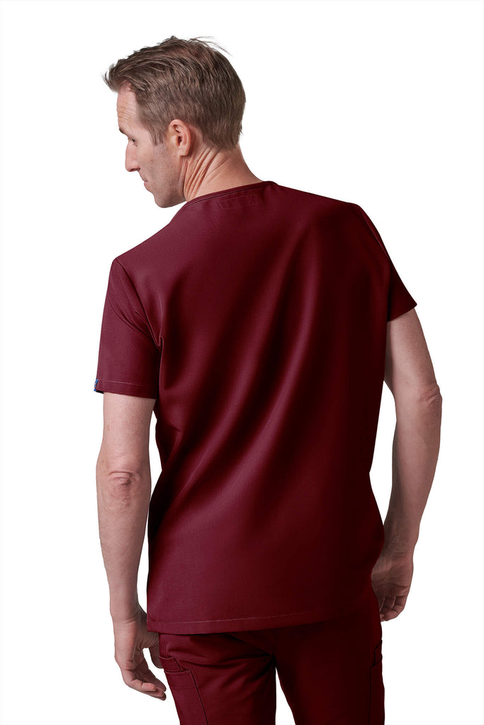 Man wearing MedTailor men's custom scrub top in Merlot Red color fabric